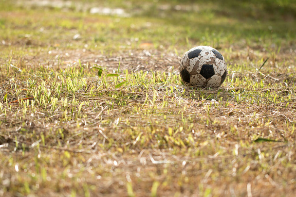 Старый футбольный мяч на траве хуже, Плохое футбольное поле в сельской местности. - Фото, изображение