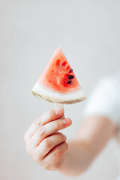 Womans hand holding a piece of watermelon on a stick - Photo, Image