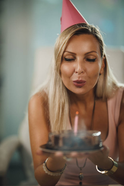 Alone attractive woman have birthday celebration at home during pandemic isolation and have video call with friends. She holding birthday cake with lighted candles. - Photo, Image