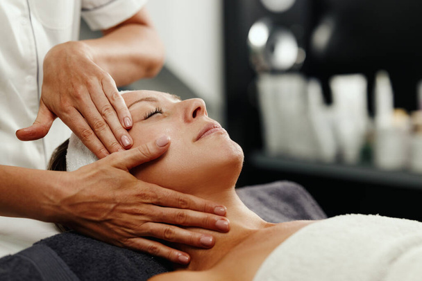 Shot of a beautiful mature woman enjoying face massage at the beauty salon. - Photo, Image