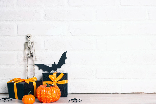 Halloween holiday background with gifts and decorations against a white brick wall. Copy space for text. - Foto, imagen