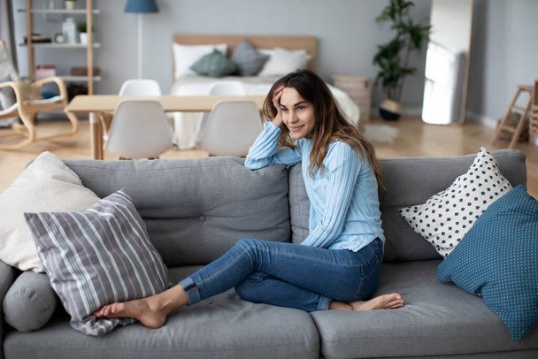 Relaxed smiling woman sitting on sofa at home. Domestic life. - Foto, imagen