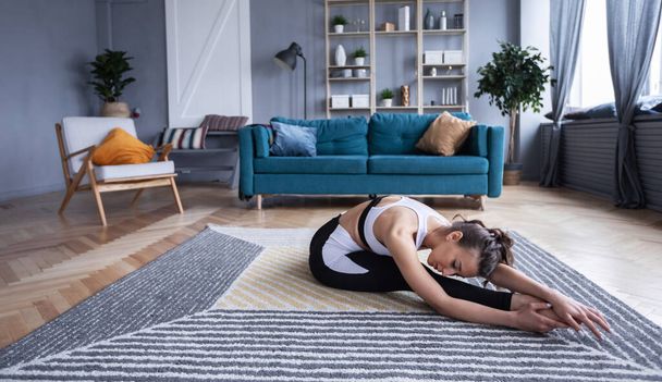 Beautiful woman doing exercise, practicing yoga, sporty girl wearing black sportswear working out indoors. - Фото, зображення