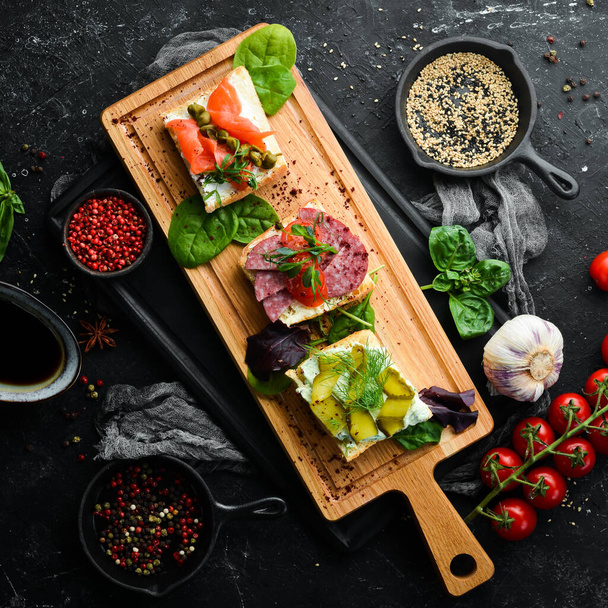 Set of sandwiches with vegetables and salmon on a wooden board. Top view. Rustic style. - Fotoğraf, Görsel