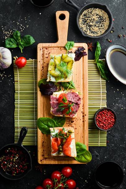 Set of sandwiches with vegetables and salmon on a wooden board. Top view. Rustic style. - Foto, immagini