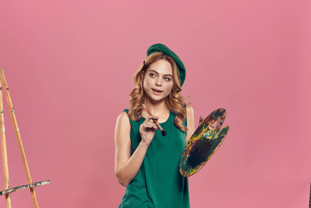 緑のベレー帽を身に着けている女性アーティストペイントブラシ創造的な趣味ピンクの背景 - 写真・画像