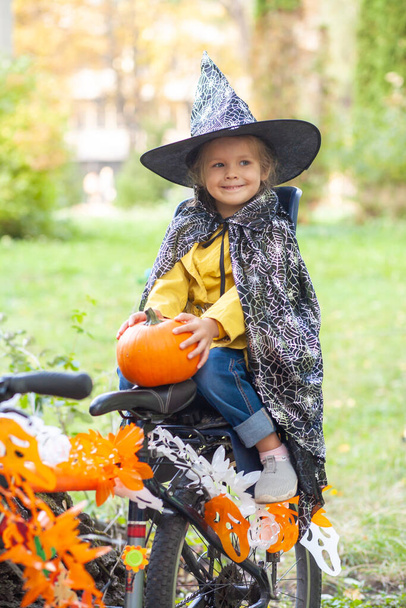 Uma menina em um feriado de Halloween na natureza com bicicleta  - Foto, Imagem