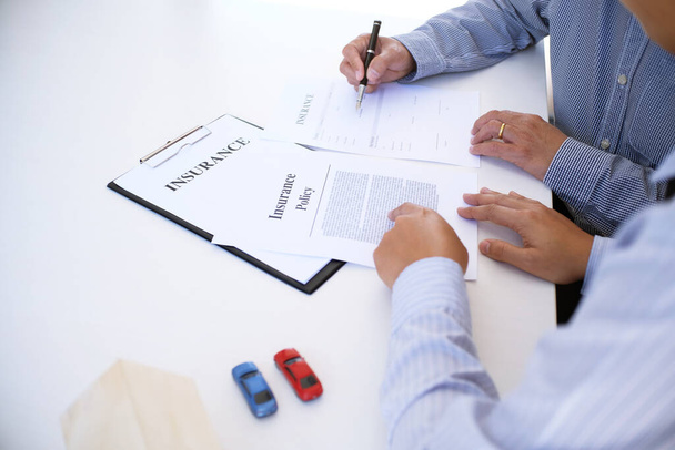 Verkoopmanager geeft advies aanvraagformulier document, overweegt hypotheek lening aanbod voor auto en huis verzekering - Foto, afbeelding