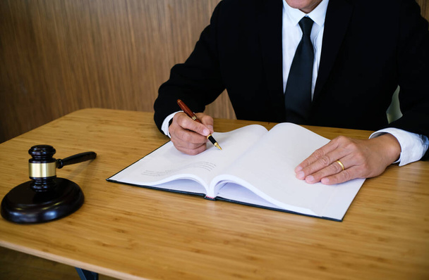 Az ügyvéd úr aláírt szerződést mutat be az ügyfélnek kalapáccsal és jogszabállyal. igazságszolgáltatás és ügyvéd fogalma - Fotó, kép