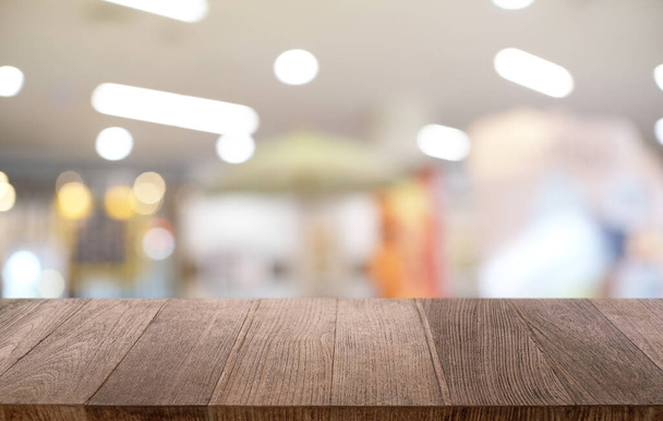 Пустой тёмный деревянный стол перед абстрактным размытым боке-фоном ресторана. можно использовать для показа или монтажа своих продуктов. - Фото, изображение