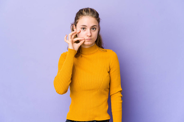 Молода біла жінка на фіолетовому фоні з пальцями на губах тримає таємницю
. - Фото, зображення