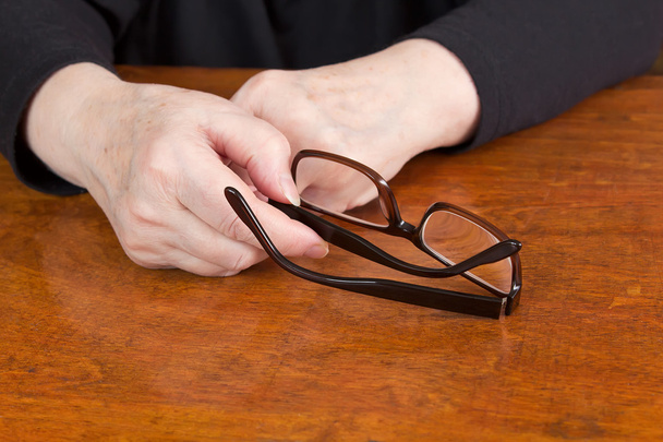 Mulher segurando seus óculos em suas mãos
 - Foto, Imagem