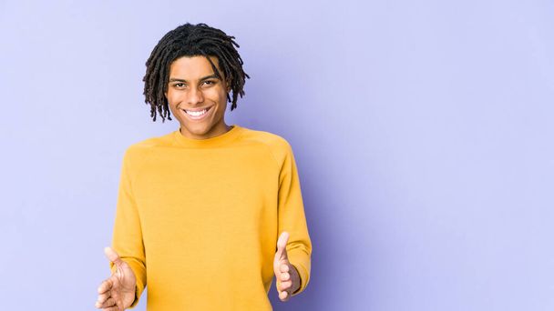 Fiatal fekete férfi visel raszta frizura gazdaság valami két kézzel, termék bemutatása. - Fotó, kép