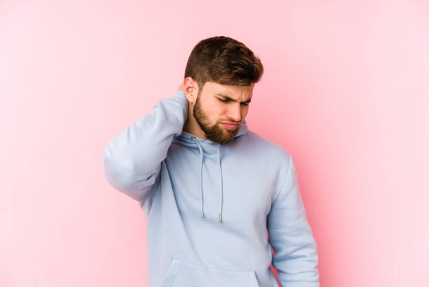 Junge kaukasische Mann isoliert auf rosa Hintergrund leiden Nackenschmerzen aufgrund sitzenden Lebensstils. - Foto, Bild