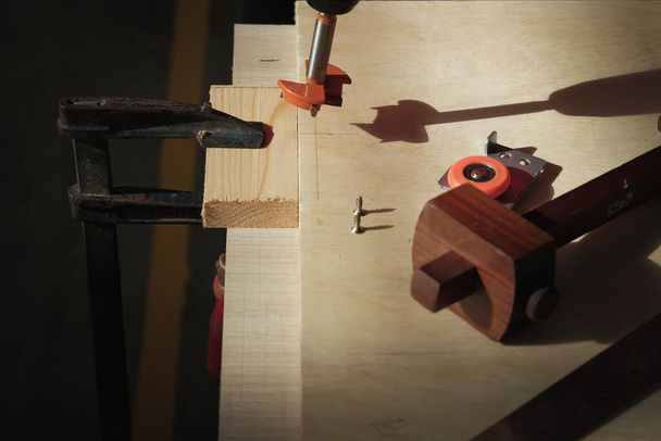 Forstner bit, rodillo de puerta corredera, indicador de marcado, tornillos e intente cuadrado en la mesa de trabajo de madera - Foto, imagen
