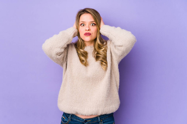 Young caucasian woman isolated on purple background covering ears with hands trying not to hear too loud sound. - 写真・画像