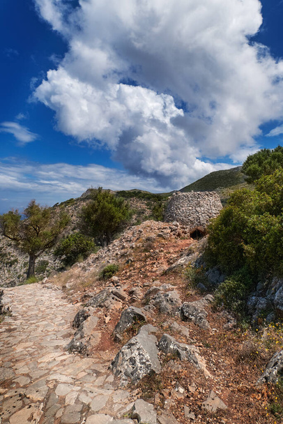 Greek or Cretan landscape, hills with spring foliage, bushes, olive trees, rocky path, mitato. Blue sky with clouds. Akrotiri, Chania, Crete, Greece - Fotó, kép