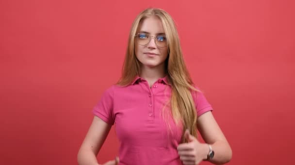 Porträt einer attraktiven jungen Frau mit einem Daumen nach oben auf rotem Hintergrund - Filmmaterial, Video