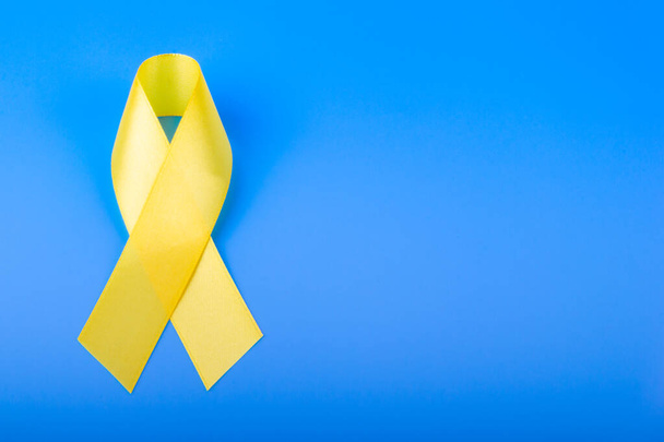Yellow ribbon on blue background. Cancer concept. - Фото, зображення