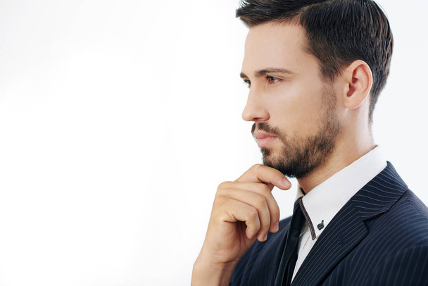 Portrait of pensive serious young businessman touching chin and looking in front of him, isolated on white - Φωτογραφία, εικόνα