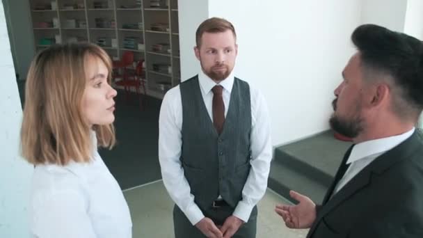 Gruppe von drei ernsthaften Büroangestellten, die zusammenstehen und über Probleme sprechen, mit denen sie konfrontiert sind, während sie versuchen, eine Einigung zu erzielen - Filmmaterial, Video