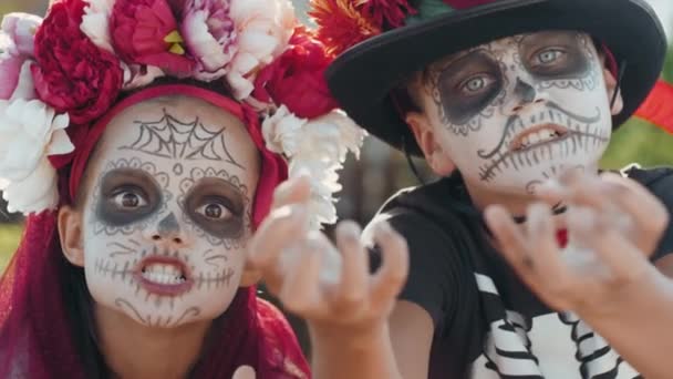 Portrait de fille et de garçon portant des costumes d'Halloween et du maquillage regardant la caméra et agissant effrayant. Ils font des visages et atteignent leurs mains à la caméra - Séquence, vidéo