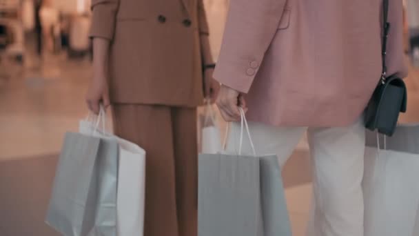 Alışveriş torbaları taşıyan ve alışveriş merkezinde sohbet eden, şık kıyafetler içindeki tanınmayan genç kadınların orta sınıf yavaşlığı. - Video, Çekim