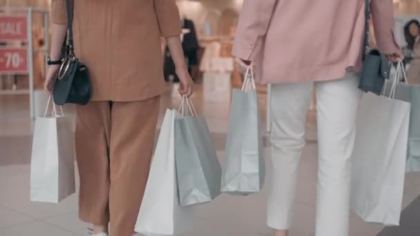 ゆっくり追跡の認識できない若い女性を運ぶショッピングバッグと歩行にブティック - 映像、動画