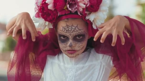 Retrato de mano de niña usando maquillaje y disfraz de Halloween haciendo caras de miedo para la cámara - Metraje, vídeo