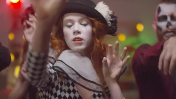 Handheld-Portraitaufnahme einer jungen Frau im Clownskostüm, die mit ihren Freunden vor der Kamera tanzt - Filmmaterial, Video