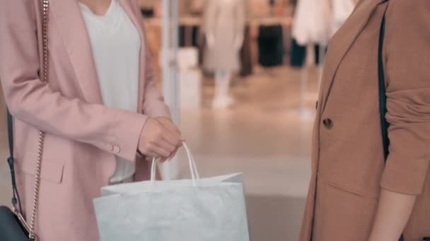 Mid-section πλάνο νεαρών γυναικών φίλων με κομψά ρούχα που στέκονται έξω από το κατάστημα ρούχων και συζητούν τις αγορές τους - Πλάνα, βίντεο