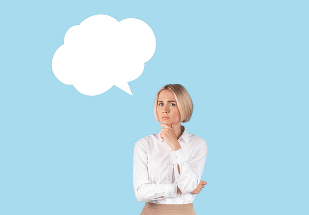 Puzzled zakenvrouw met spraakbel op blauwe studio achtergrond, mockup voor ontwerp - Foto, afbeelding