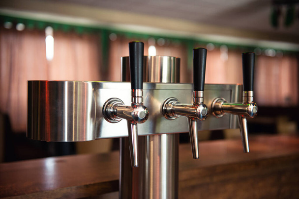 Пивний кран у барі, сучасні металеві сидрні крани в ряд
 - Фото, зображення