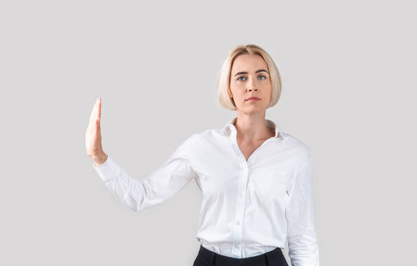 Sebevědomý zralý obchodní dáma gesturing STOP na světle šedé pozadí studia - Fotografie, Obrázek