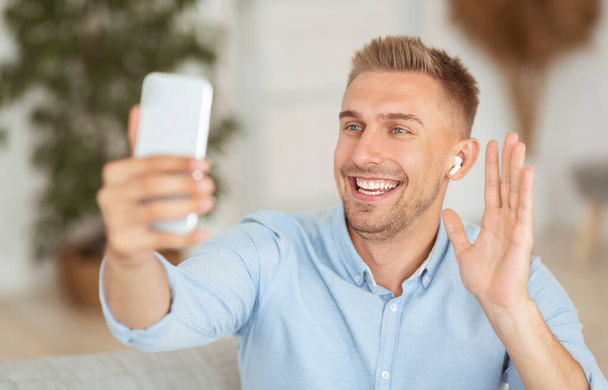 Щасливий чоловік використовує мобільний телефон для відеодзвінків і махає
 - Фото, зображення