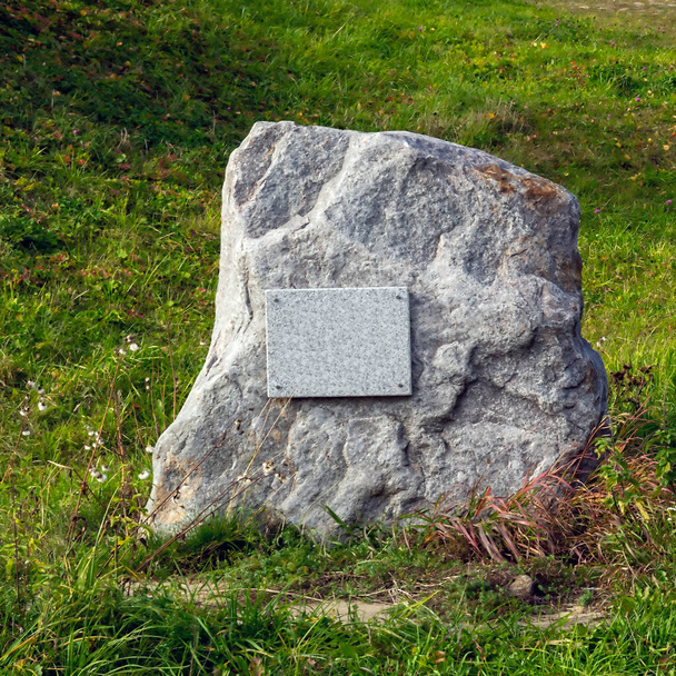 Memorial stone in the grass with a sign - 写真・画像