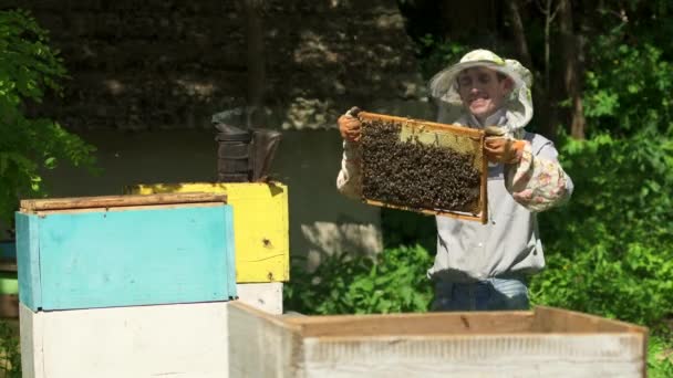O apicultor sorri para a câmera segurando uma célula de mel em suas mãos. - Filmagem, Vídeo