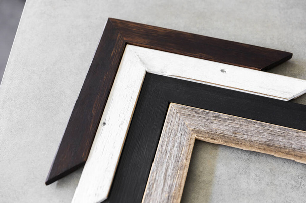 Various recycled timber picture frame corners on display on cement table surface. - Foto, Imagem