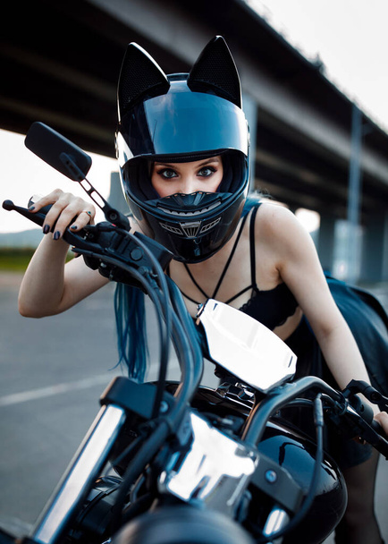 セクシーな女の子バイクの車輪の後ろのヘルメットの中のセクシーな女の子。バイクの車輪の後ろのヘルメットに. - 写真・画像