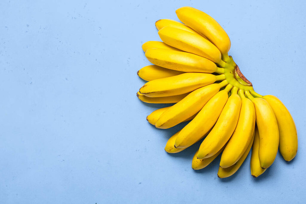Organic rip of mini bananas on blue background. - Fotó, kép