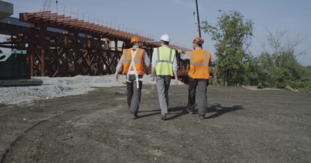 Profesjonalni inżynierowie idący w kierunku niedokończonego mostu - Materiał filmowy, wideo