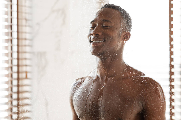 szczęśliwy Afrykanin człowiek biorąc zimny prysznic orzeźwiający w rano kryty - Zdjęcie, obraz
