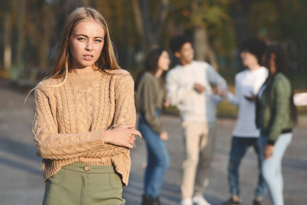 Frustrada chica rubia de pie sobre el grupo de adolescentes - Foto, Imagen