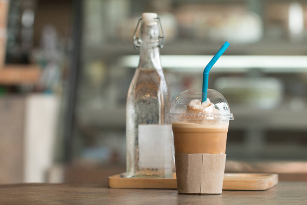 Buzlu capucino frape bardaklı kahve ahşap masada bulanık kahve dükkanlı içki.. - Fotoğraf, Görsel