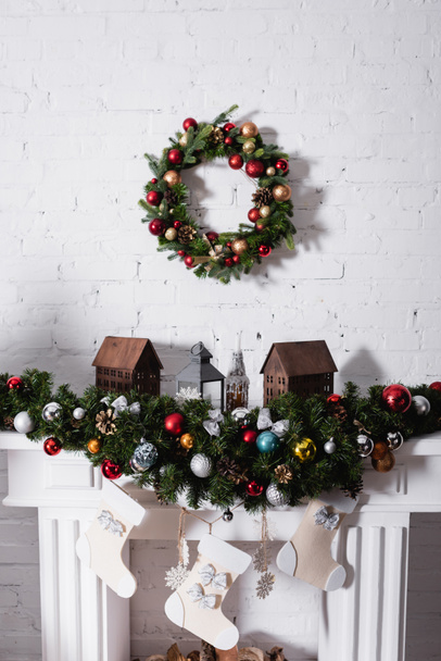 Christmas wreath above fireplace decorated with christmas balls and stockings - Φωτογραφία, εικόνα