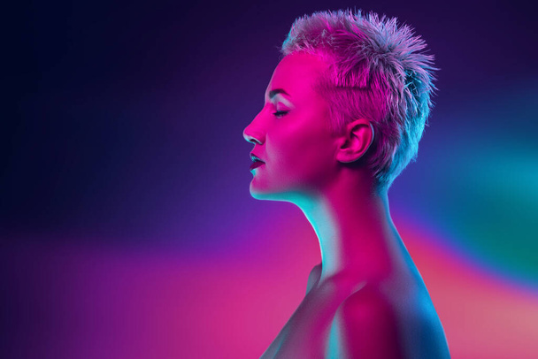 Portrait of female fashion model in neon light on dark studio background. - 写真・画像