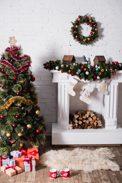 Gift boxes near festive pine and christmas wreath above decorated fireplace - Photo, Image