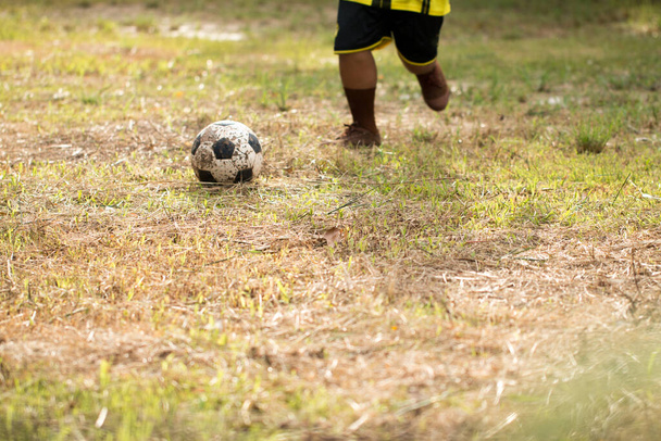 Mladý asijský chlapec hraje fotbal na venkově. - Fotografie, Obrázek