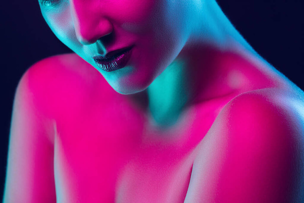 Portrait of female fashion model in neon light on dark studio background. - Valokuva, kuva