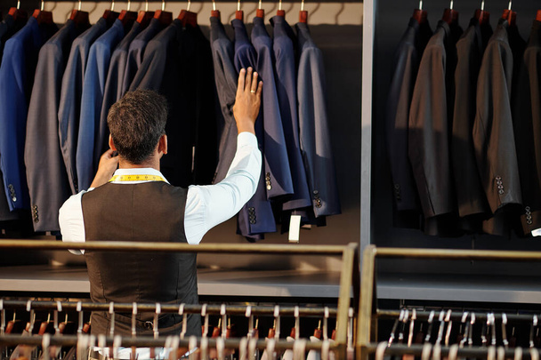 Tailor έλεγχο τελειώσει σακάκια που κρέμονται σε ράγα στο ατελιέ του - Φωτογραφία, εικόνα